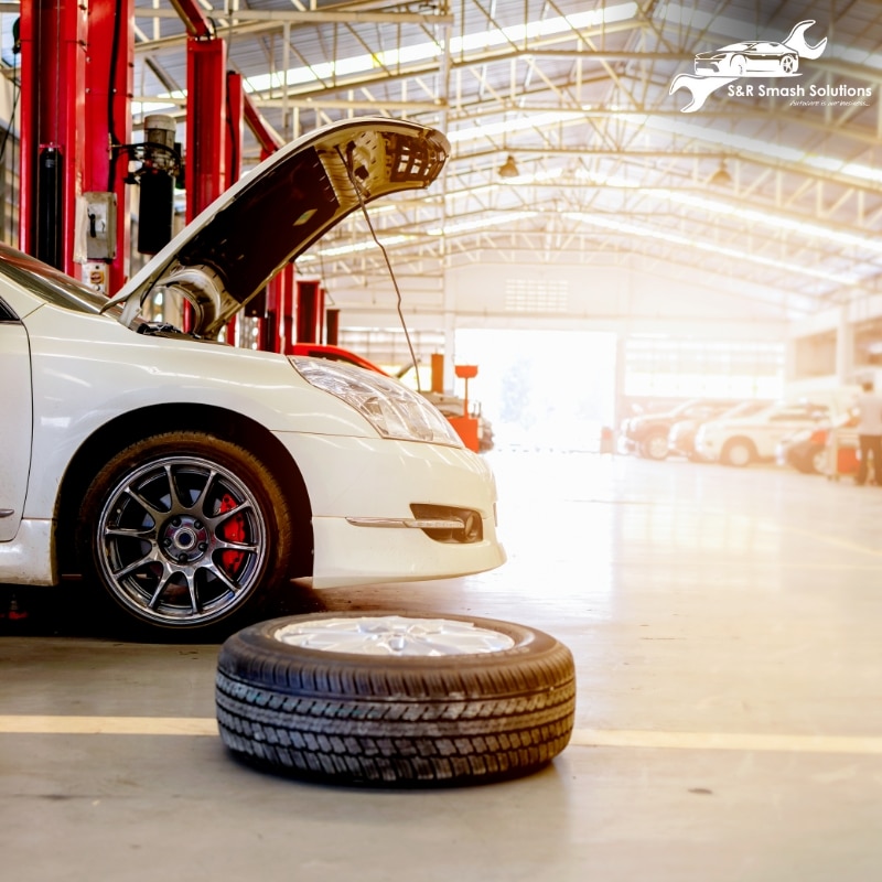 A vehicle in a garage with a tire on the floor, highlighting the work of a smash repairer.